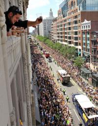 Toast of the town: Kostas Klokelis, from Framingham, Mass., toasts from a window overlooking the duck boats carrying the Boston Bruins and their families as they roll through downtown during a rally in celebration of their NHL hockey Stanley Cup playoff victory Saturday, June 18. AP Photo